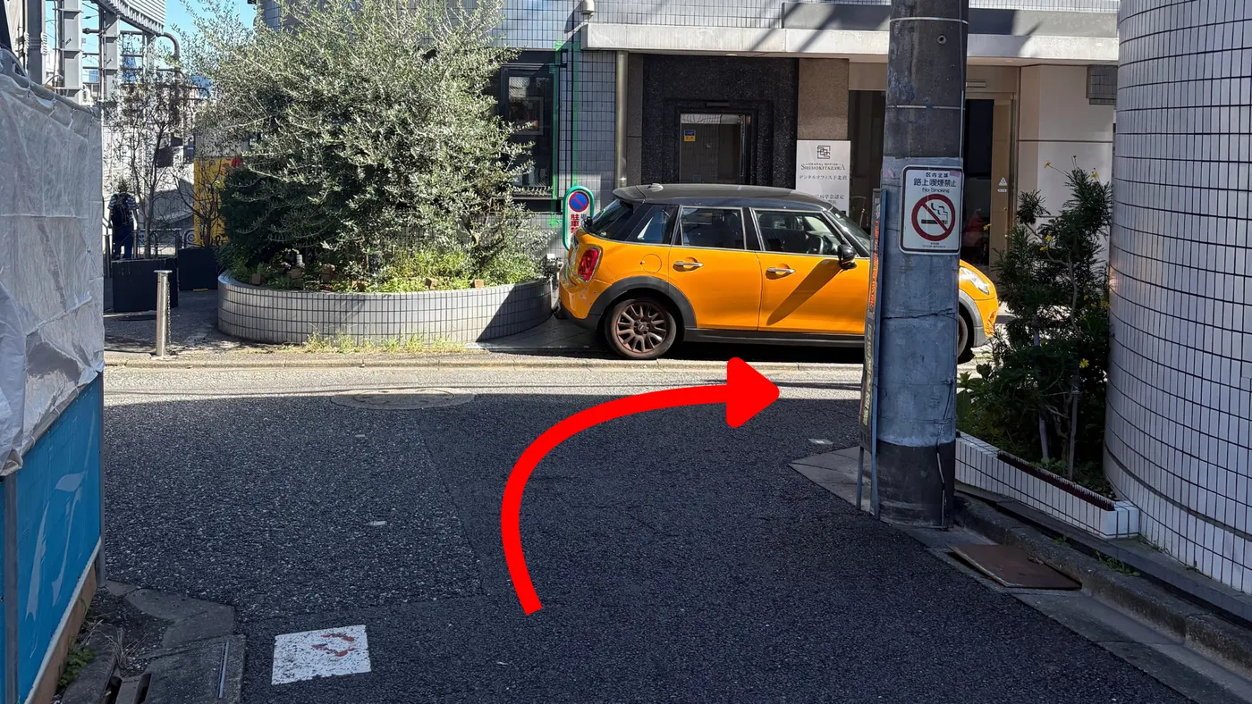 交差点を右方向へ進む道順。右手に黄色い車が見える